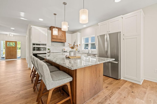 kitchen featuring white cabinetry, a center island, stainless steel appliances, and decorative light fixtures