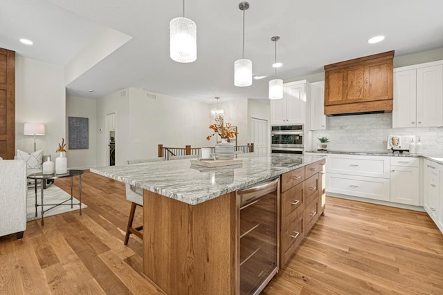 kitchen featuring wine cooler, white cabinetry, a center island, and light hardwood / wood-style floors