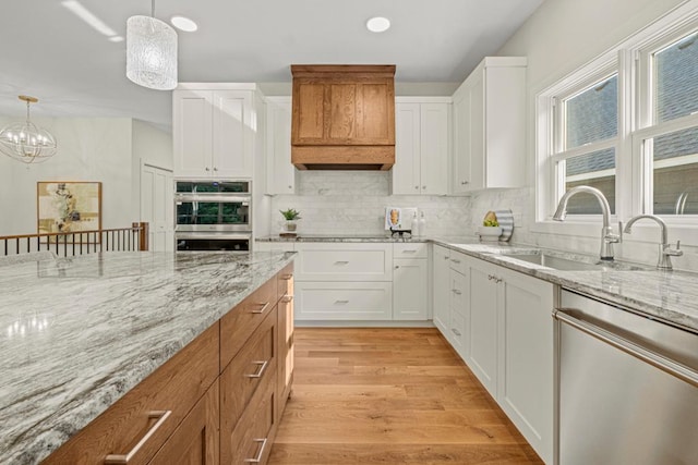 kitchen featuring appliances with stainless steel finishes, decorative light fixtures, and white cabinetry