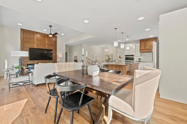 dining space with a large fireplace, ceiling fan, and light hardwood / wood-style flooring