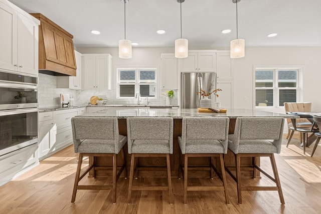 kitchen featuring white cabinetry, a kitchen island, light wood-type flooring, and appliances with stainless steel finishes