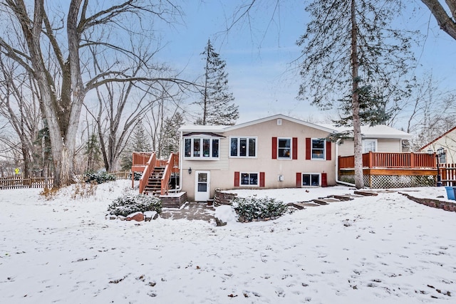 snow covered back of property featuring a wooden deck