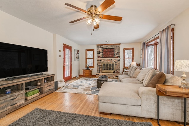 living room featuring ceiling fan, light hardwood / wood-style flooring, and a fireplace