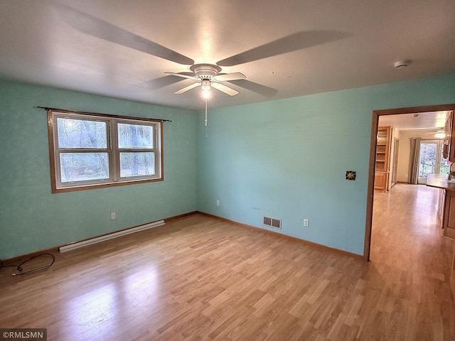 empty room with baseboard heating, ceiling fan, and light hardwood / wood-style floors