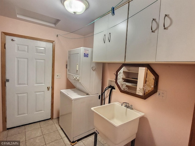 laundry room featuring sink, light tile patterned flooring, cabinets, and stacked washer and clothes dryer