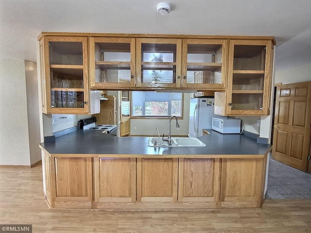 kitchen featuring kitchen peninsula, white appliances, light hardwood / wood-style flooring, and sink