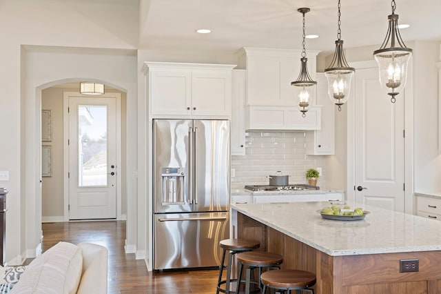 kitchen with a center island, white cabinetry, decorative light fixtures, and stainless steel appliances