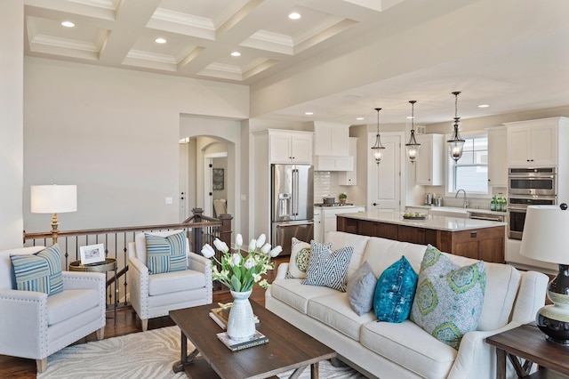 living room with sink, dark hardwood / wood-style flooring, coffered ceiling, beamed ceiling, and ornamental molding