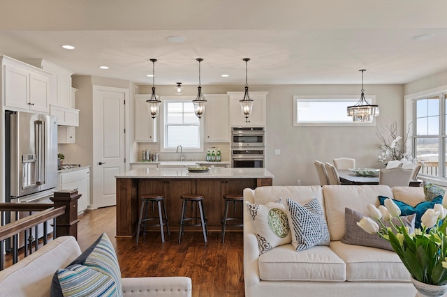 kitchen featuring appliances with stainless steel finishes, a center island, hanging light fixtures, and dark hardwood / wood-style flooring