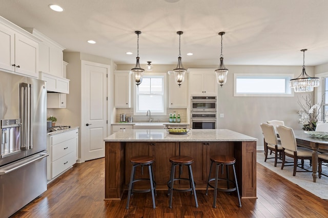 kitchen with dark hardwood / wood-style floors, appliances with stainless steel finishes, a wealth of natural light, and a kitchen island