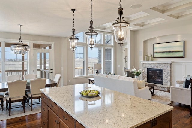 kitchen with dark hardwood / wood-style floors, light stone countertops, coffered ceiling, and hanging light fixtures