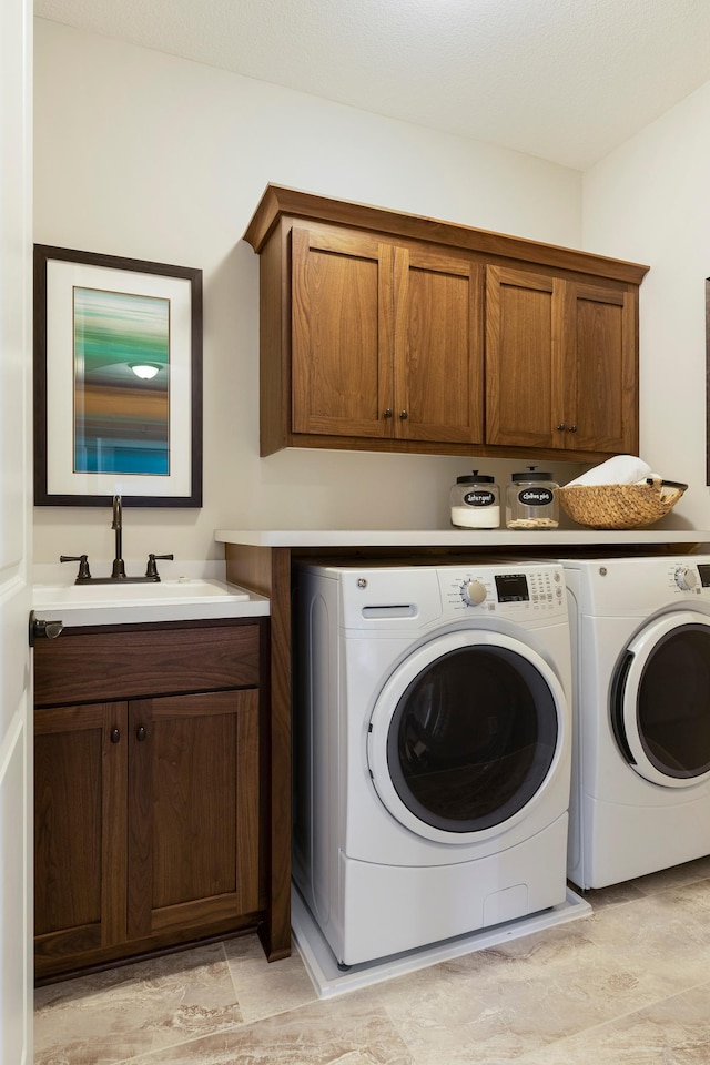 laundry room featuring sink, washing machine and dryer, and cabinets