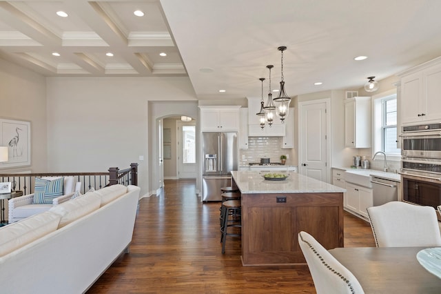 kitchen featuring decorative backsplash, appliances with stainless steel finishes, dark hardwood / wood-style floors, pendant lighting, and a center island