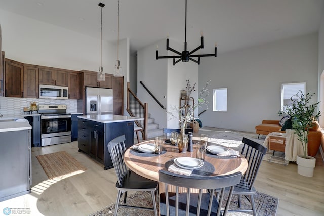 dining room featuring light wood-style floors, ceiling fan, stairs, and high vaulted ceiling