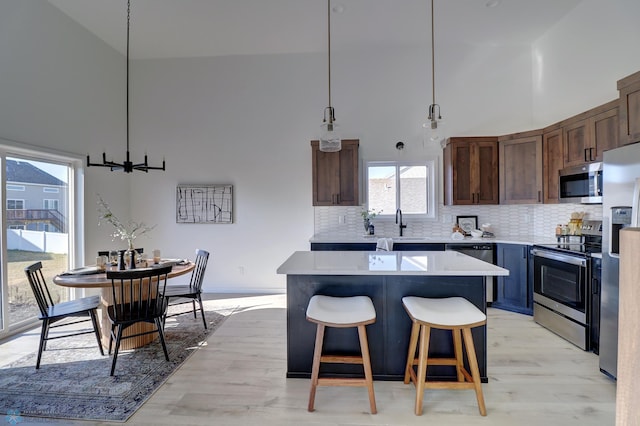 kitchen featuring tasteful backsplash, appliances with stainless steel finishes, a kitchen breakfast bar, a center island, and light countertops