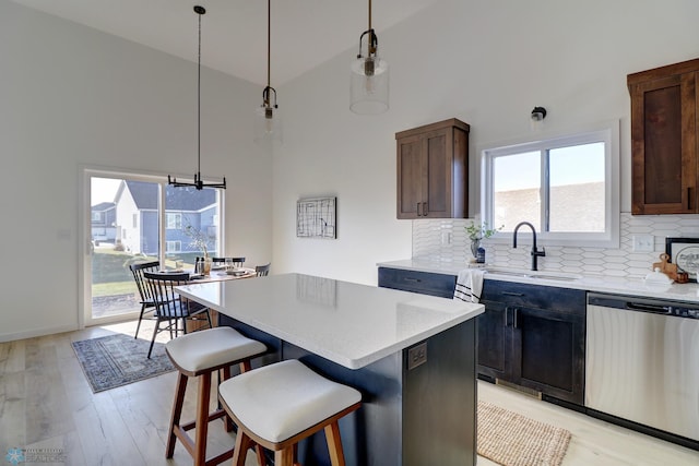 kitchen with a breakfast bar area, a sink, stainless steel dishwasher, backsplash, and a center island