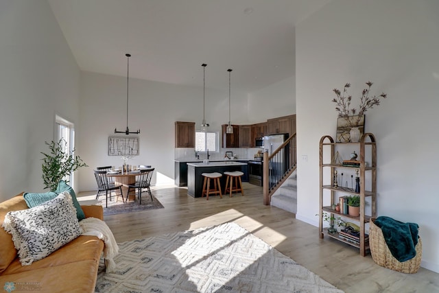 living room featuring a towering ceiling, stairway, and light wood finished floors