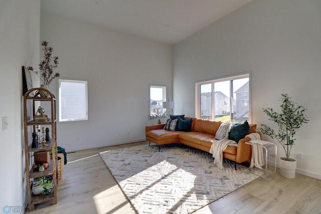 living room with a towering ceiling, baseboards, and wood finished floors