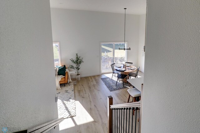 interior space with a textured wall, a high ceiling, wood finished floors, and a notable chandelier