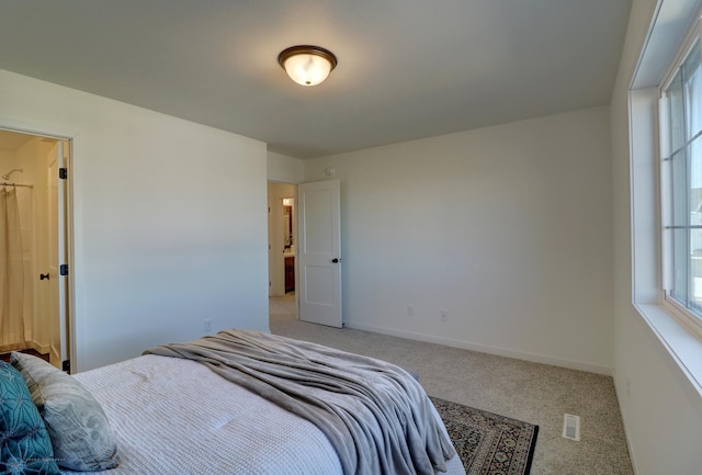 bedroom with light carpet, multiple windows, visible vents, and baseboards