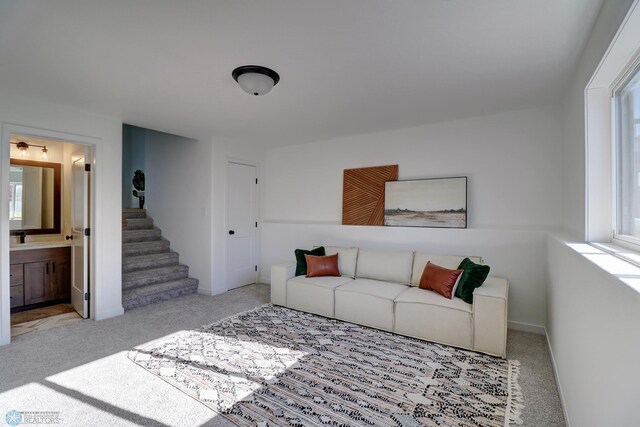 carpeted living room with stairs and baseboards