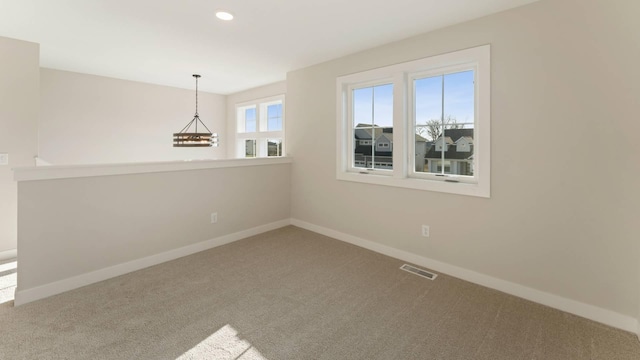 carpeted empty room with a notable chandelier