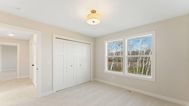 unfurnished bedroom with light colored carpet and a closet