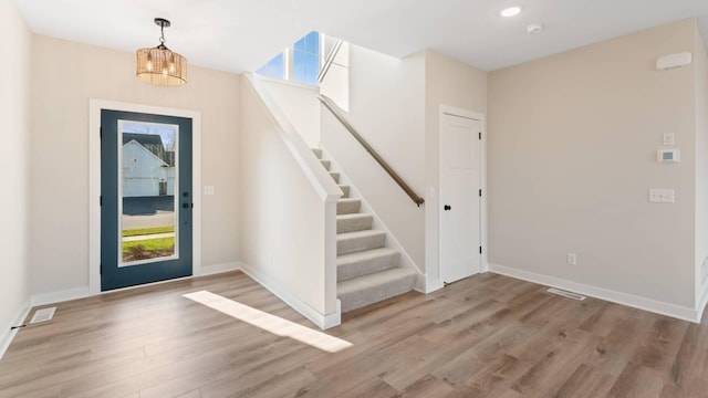 entrance foyer with light wood-type flooring, an inviting chandelier, and plenty of natural light