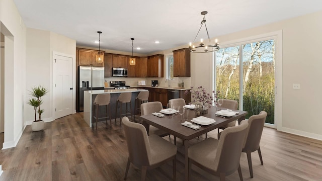 dining space with sink, dark wood-type flooring, and an inviting chandelier