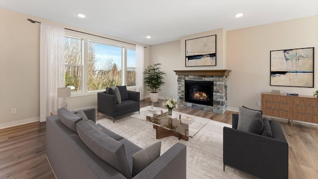 living room with a healthy amount of sunlight, hardwood / wood-style flooring, and a stone fireplace