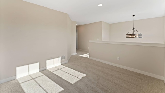 spare room with light carpet and a notable chandelier