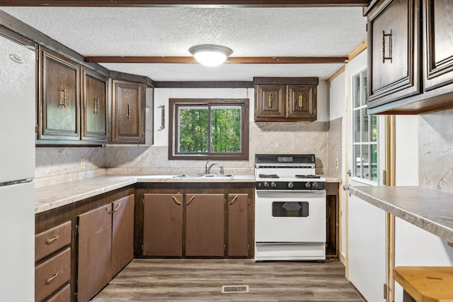 kitchen featuring dark hardwood / wood-style flooring, dark brown cabinets, sink, and white appliances