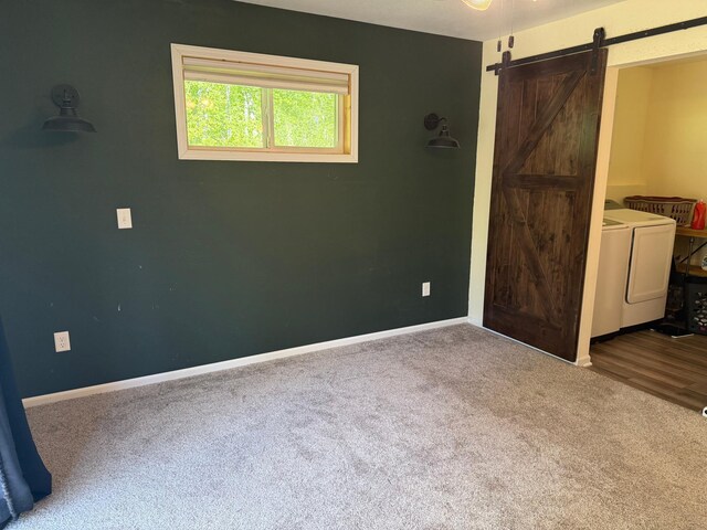 41574 Koland Rd, Sandstone Twp, MN 55072 - unfurnished bedroom with independent washer and dryer, carpet flooring, a barn door, and baseboards