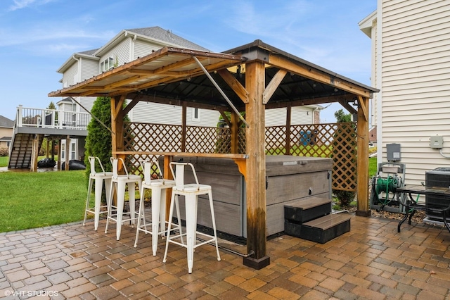 view of patio / terrace featuring a gazebo, exterior bar, and a hot tub