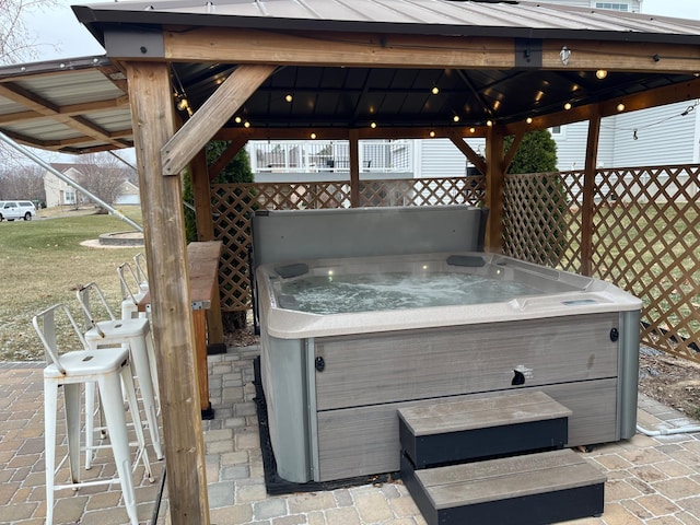 view of patio / terrace featuring a hot tub and a gazebo