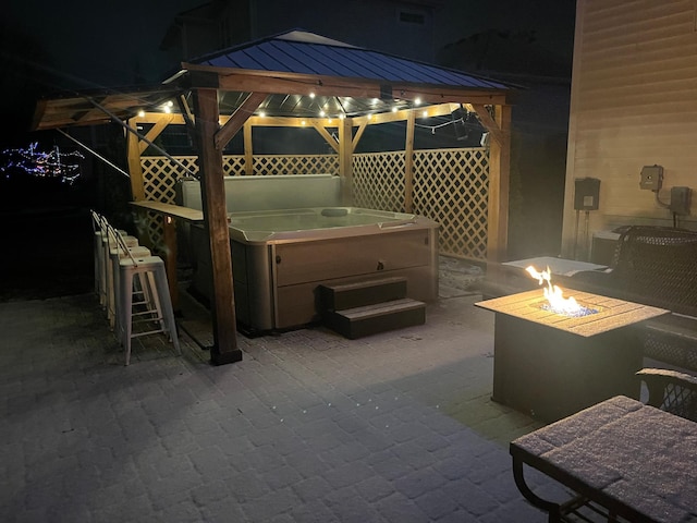 view of patio / terrace with a hot tub, a gazebo, an outdoor bar, and a fire pit