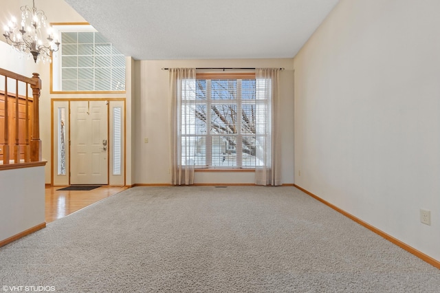 foyer entrance with light carpet and an inviting chandelier