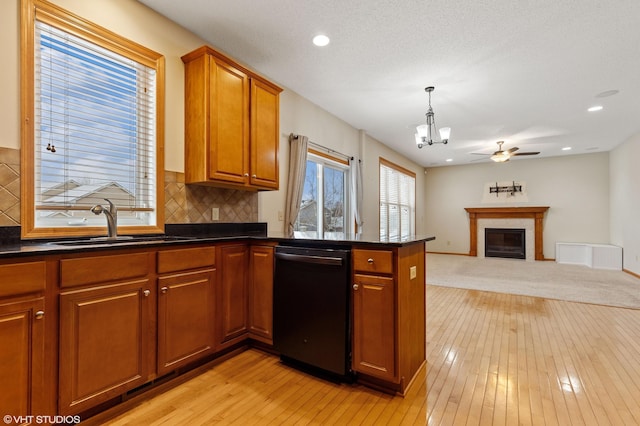 kitchen featuring sink, light wood-type flooring, black dishwasher, kitchen peninsula, and pendant lighting