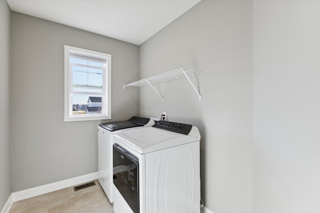 clothes washing area with separate washer and dryer and light tile patterned floors