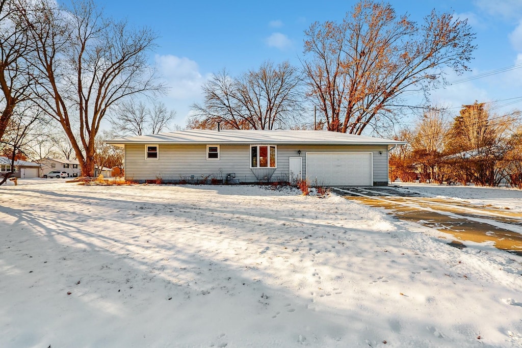 snow covered rear of property with a garage