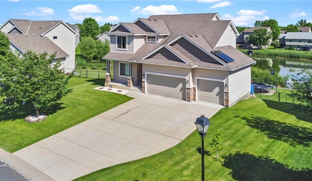 view of front of house with a garage, a front yard, and a water view