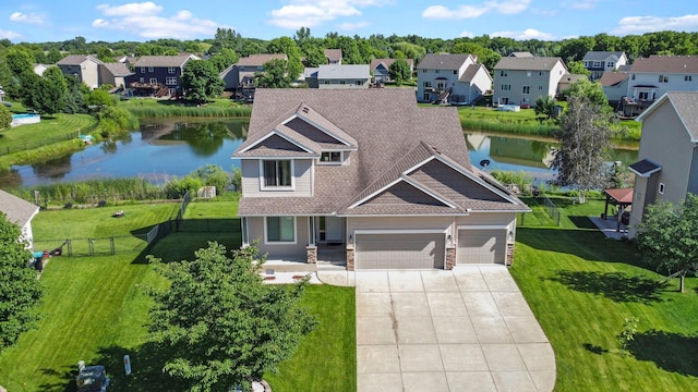 view of front of house with a garage, a water view, and a front lawn