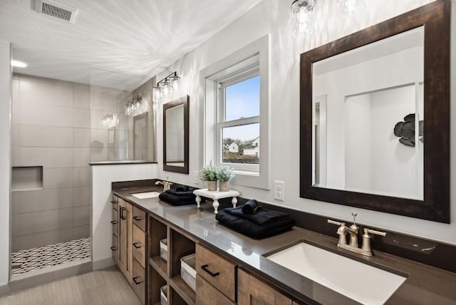 bathroom featuring a tile shower and vanity