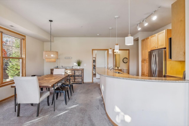 kitchen with light brown cabinets, light colored carpet, decorative light fixtures, and stainless steel fridge