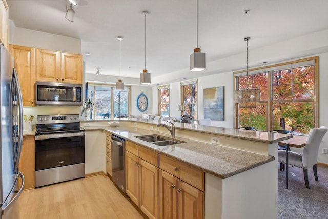 kitchen with pendant lighting, kitchen peninsula, appliances with stainless steel finishes, and sink