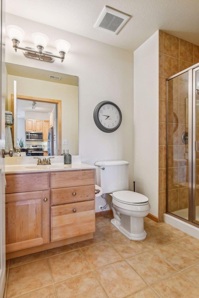 bathroom with toilet, vanity, tile patterned flooring, and a shower with door