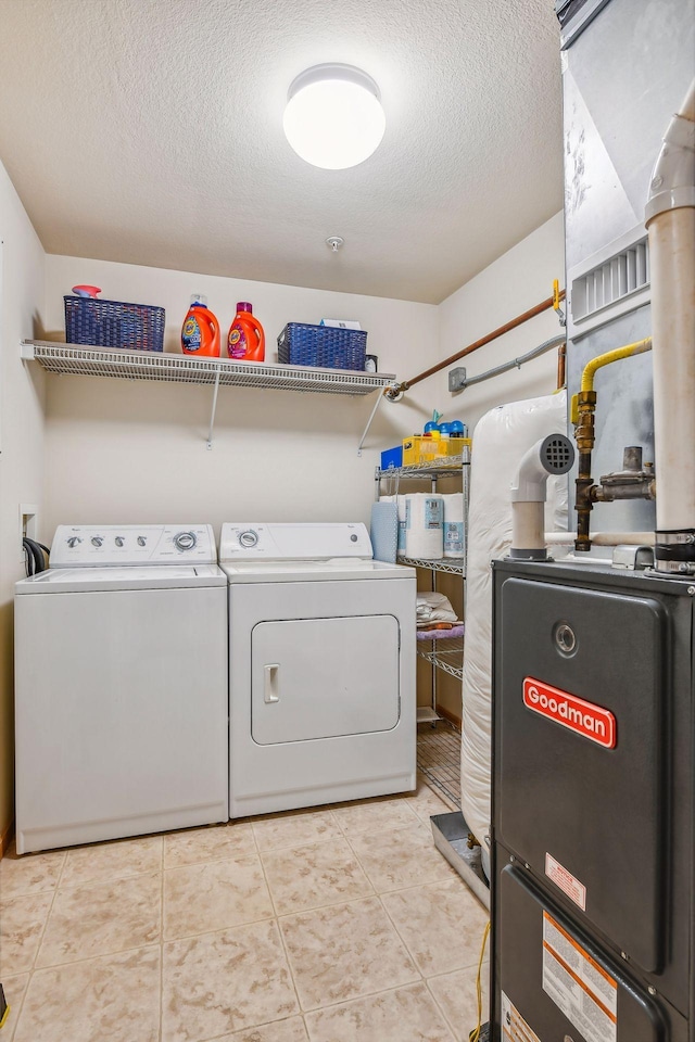 laundry room featuring washing machine and clothes dryer, a textured ceiling, and light tile patterned floors