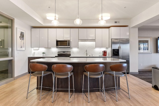 kitchen featuring hanging light fixtures, white cabinetry, appliances with stainless steel finishes, and a center island