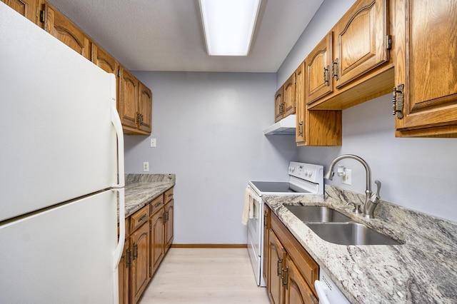 kitchen featuring light stone counters, white appliances, sink, and light wood-type flooring