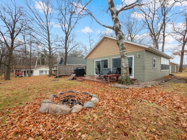 back of property featuring a fire pit, a storage unit, and a wooden deck